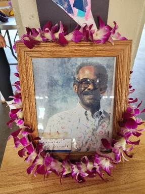 A framed picture of a person with purple flowers around it

Description automatically generated